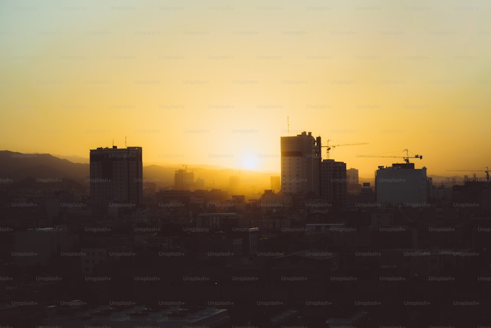 the sun is setting over a city with tall buildings