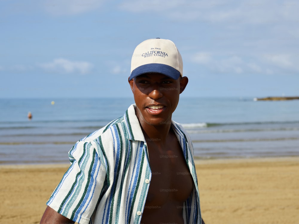 a man standing on a beach wearing a hat