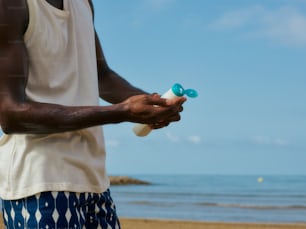 a man standing on a beach holding a bottle