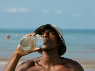 a man drinking a bottle of water on the beach