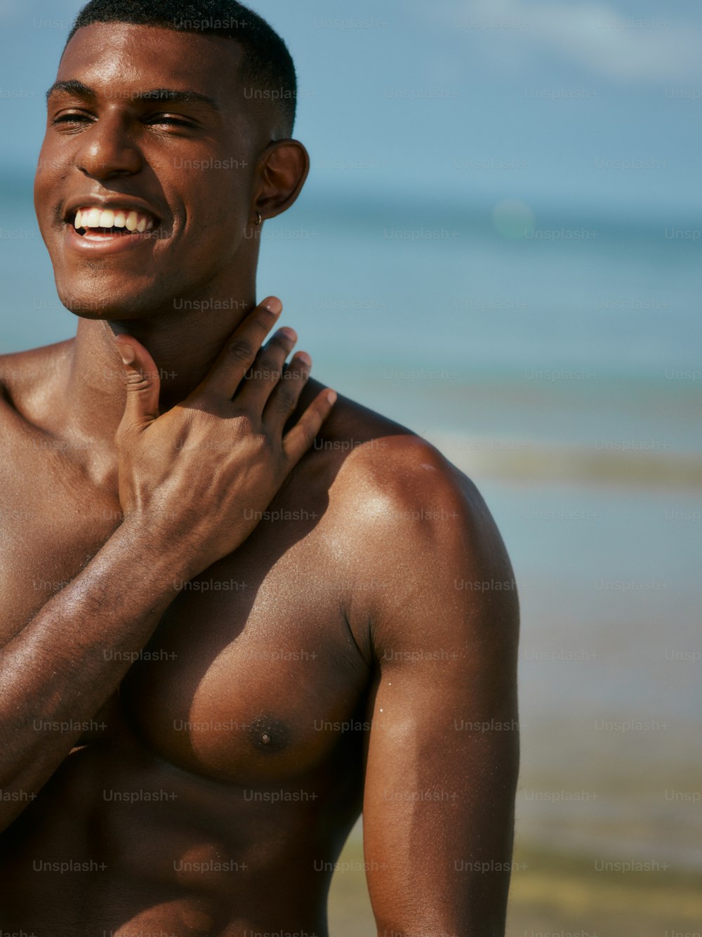 a shirtless man standing on a beach next to the ocean