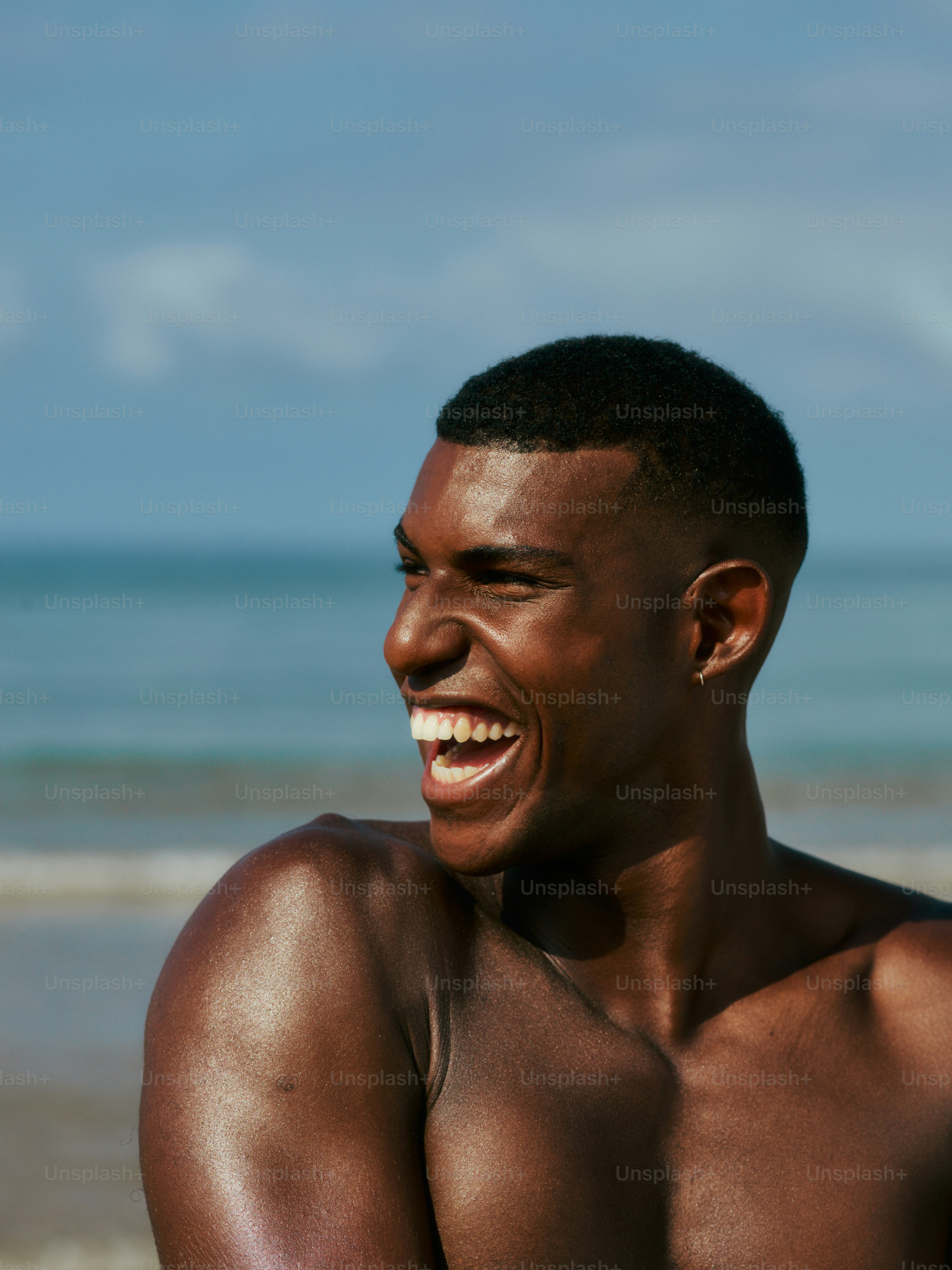 a man with no shirt on standing on a beach
