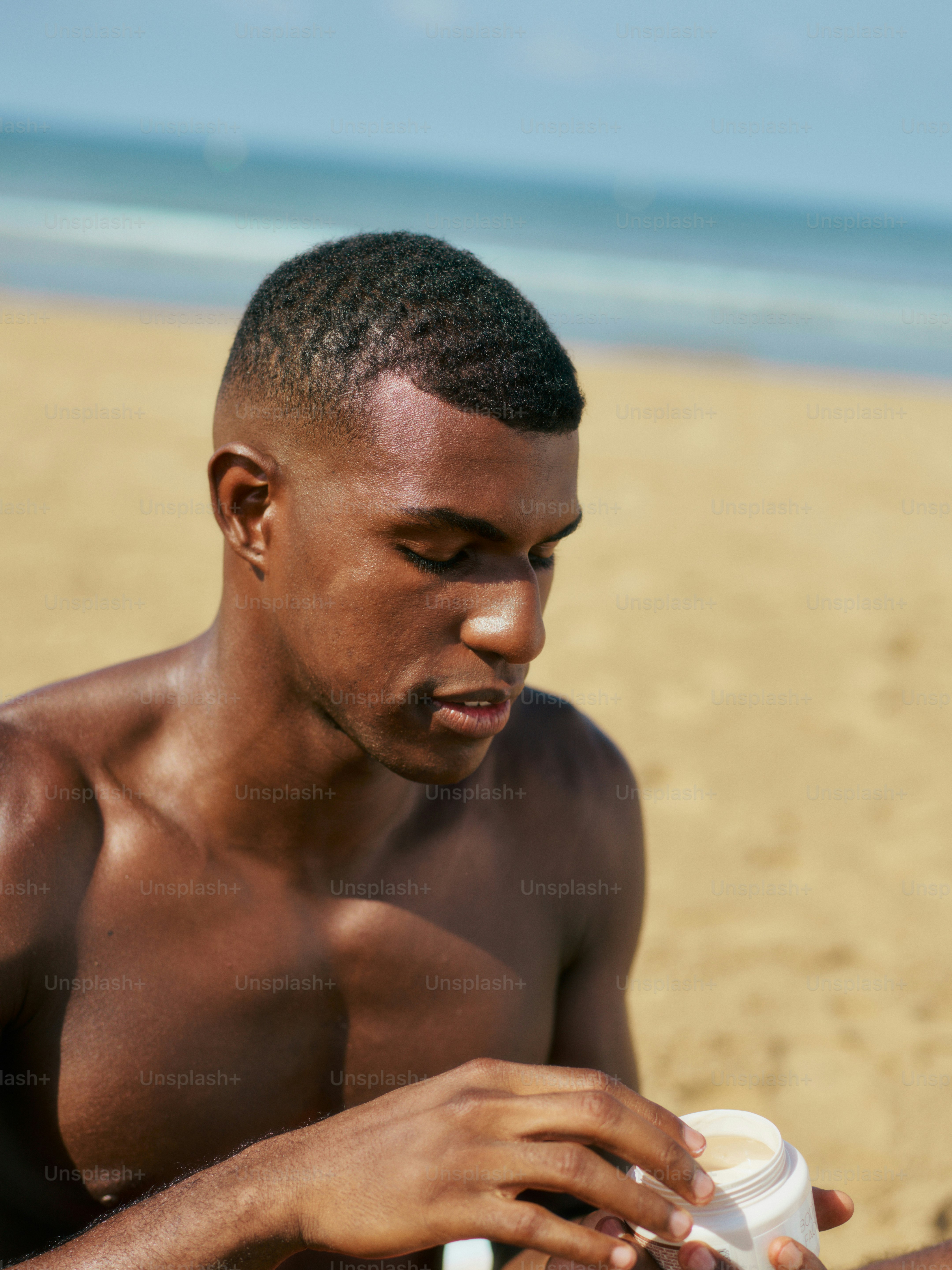 a man sitting on a beach holding a cup of coffee