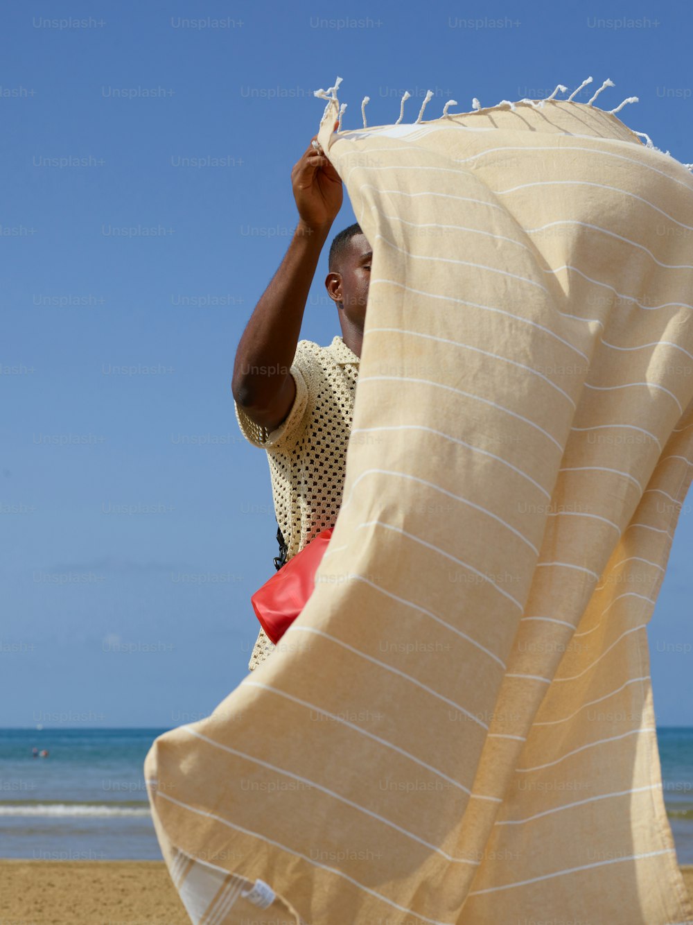 毛布の下で浜辺に立つ男