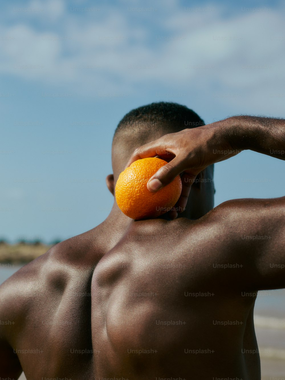Un hombre sosteniendo una naranja en su cara