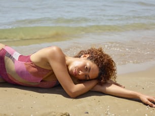 a woman laying on a beach next to the ocean