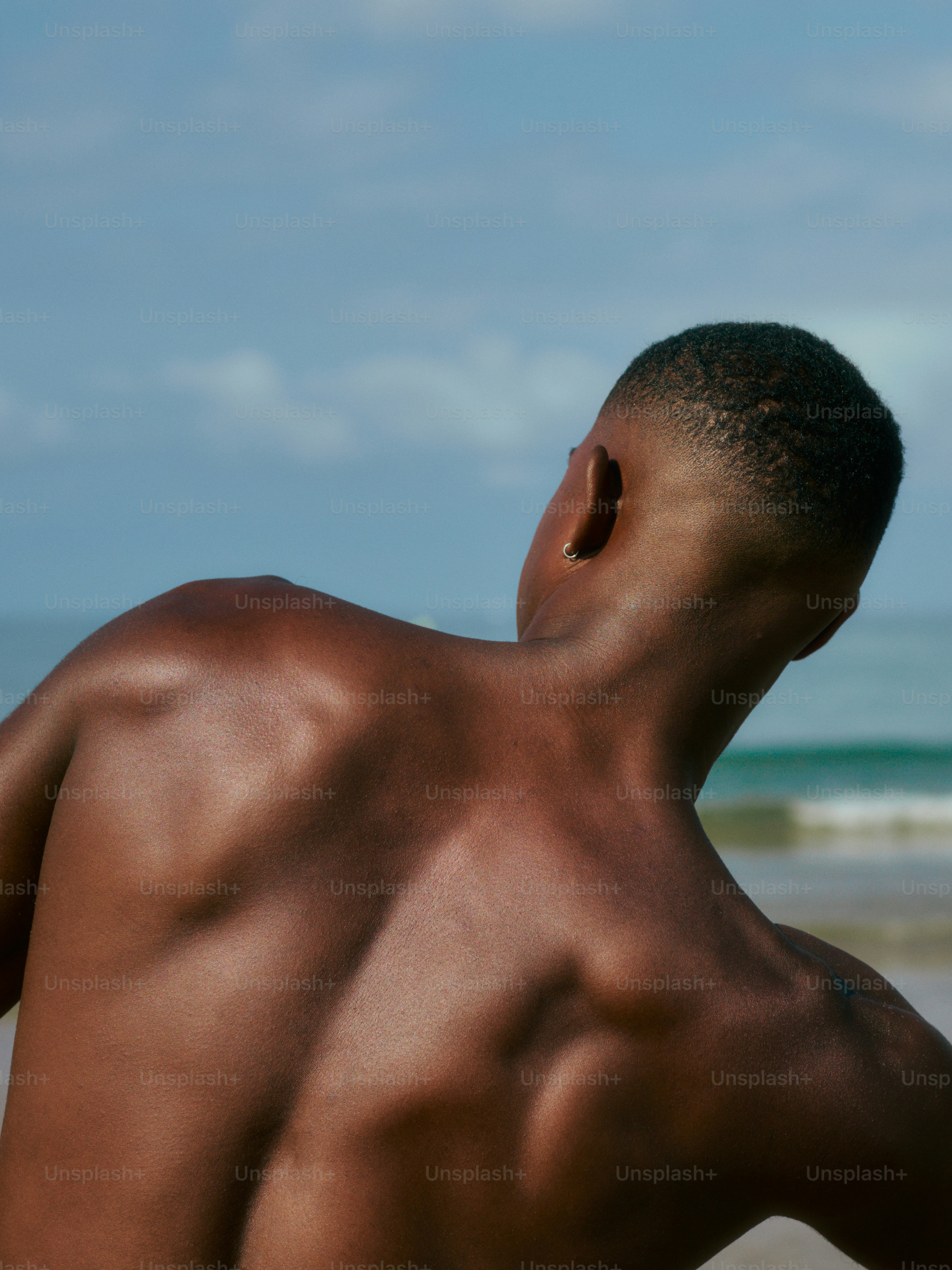a man without a shirt standing on a beach