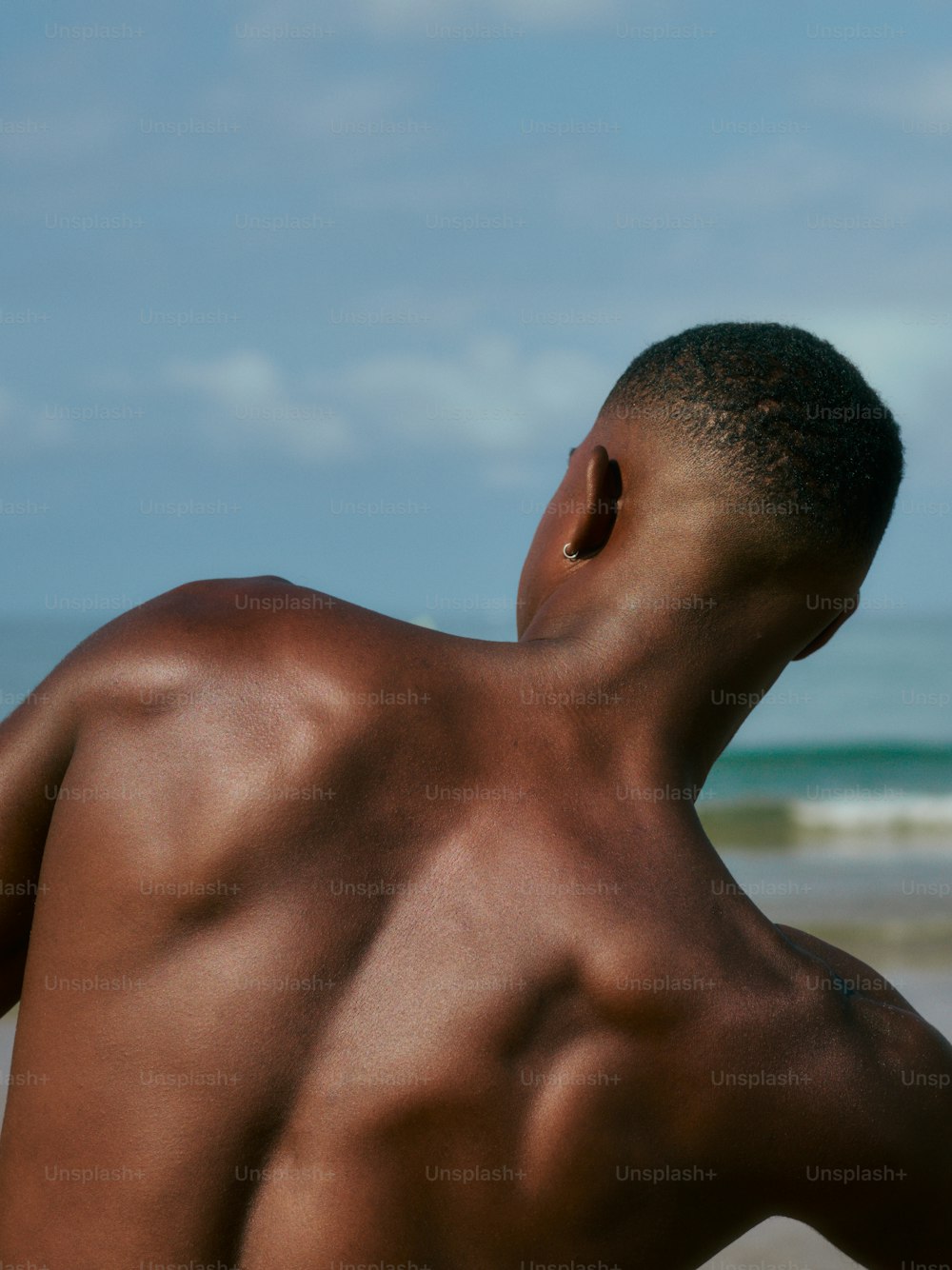 a man without a shirt standing on a beach