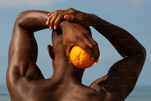 um homem segurando uma laranja no rosto