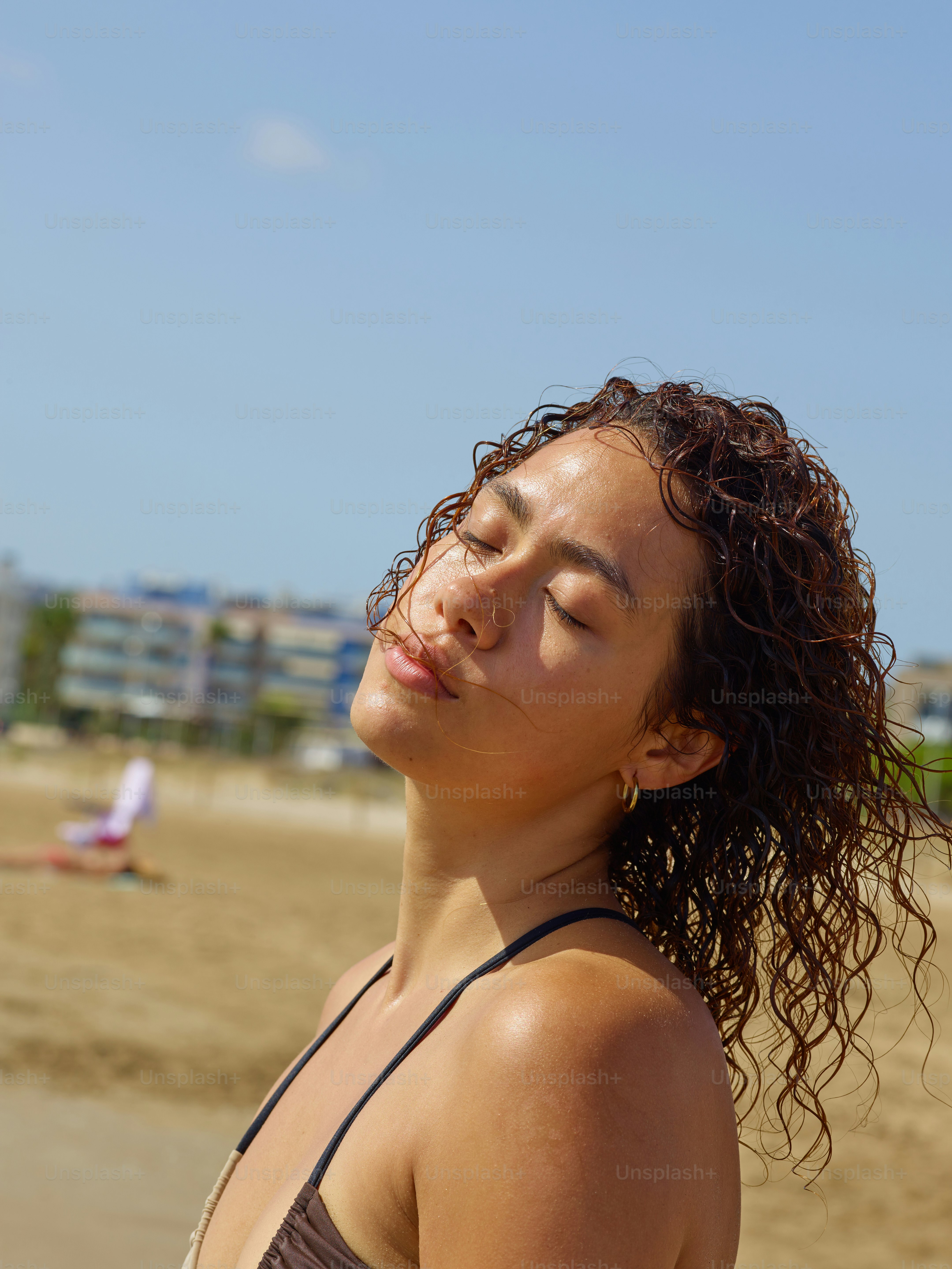 a woman standing on a beach with her eyes closed
