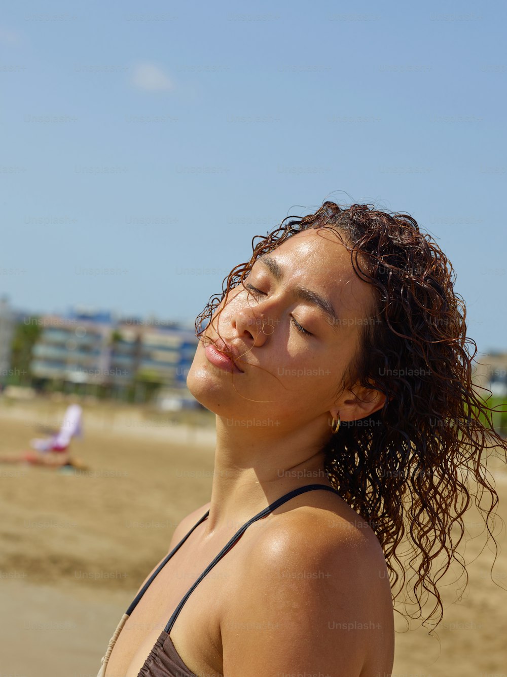a woman standing on a beach with her eyes closed