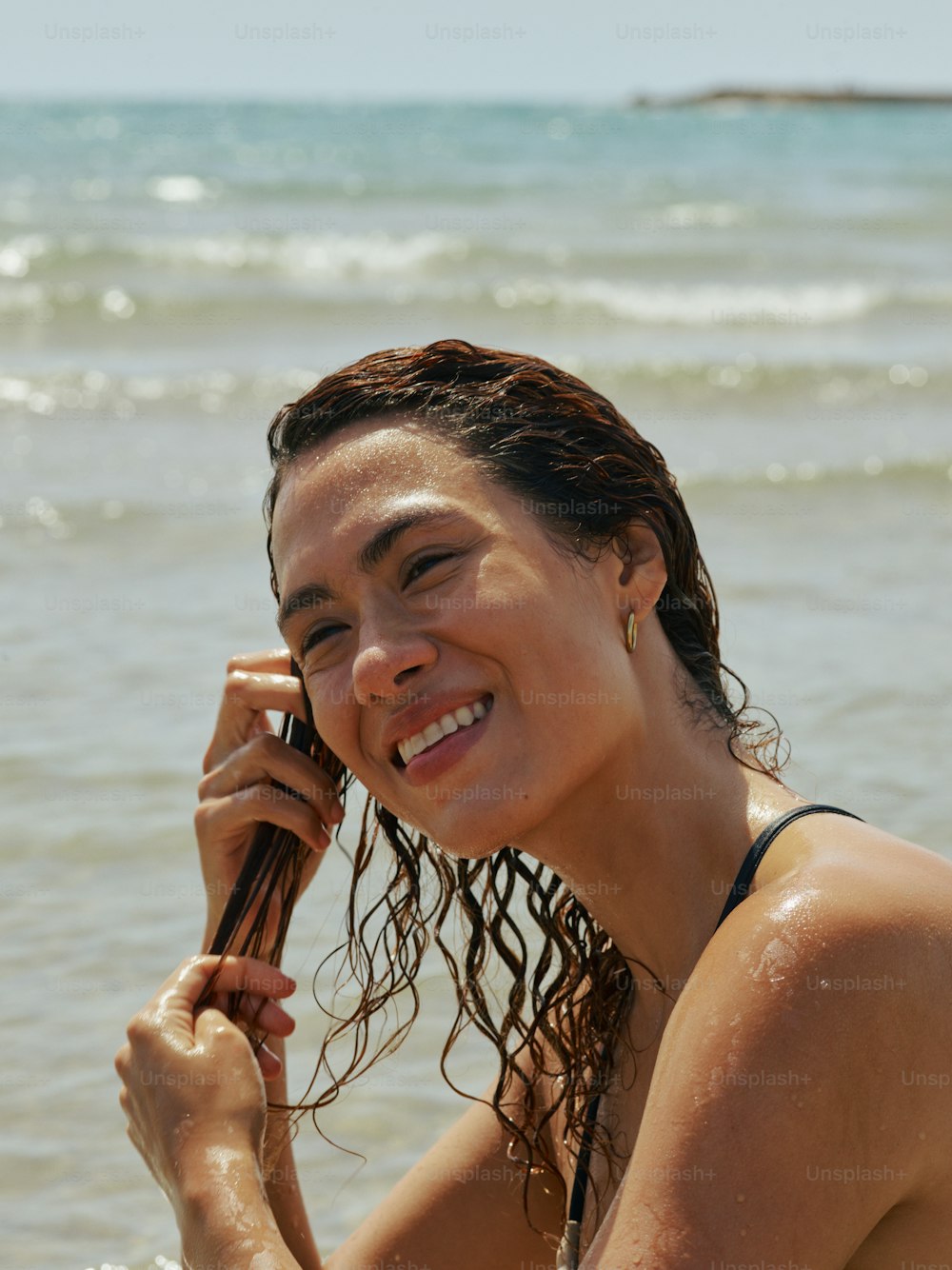 Una mujer en la playa hablando por teléfono celular