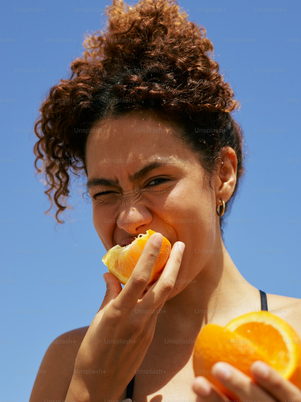 a woman is eating an orange outside