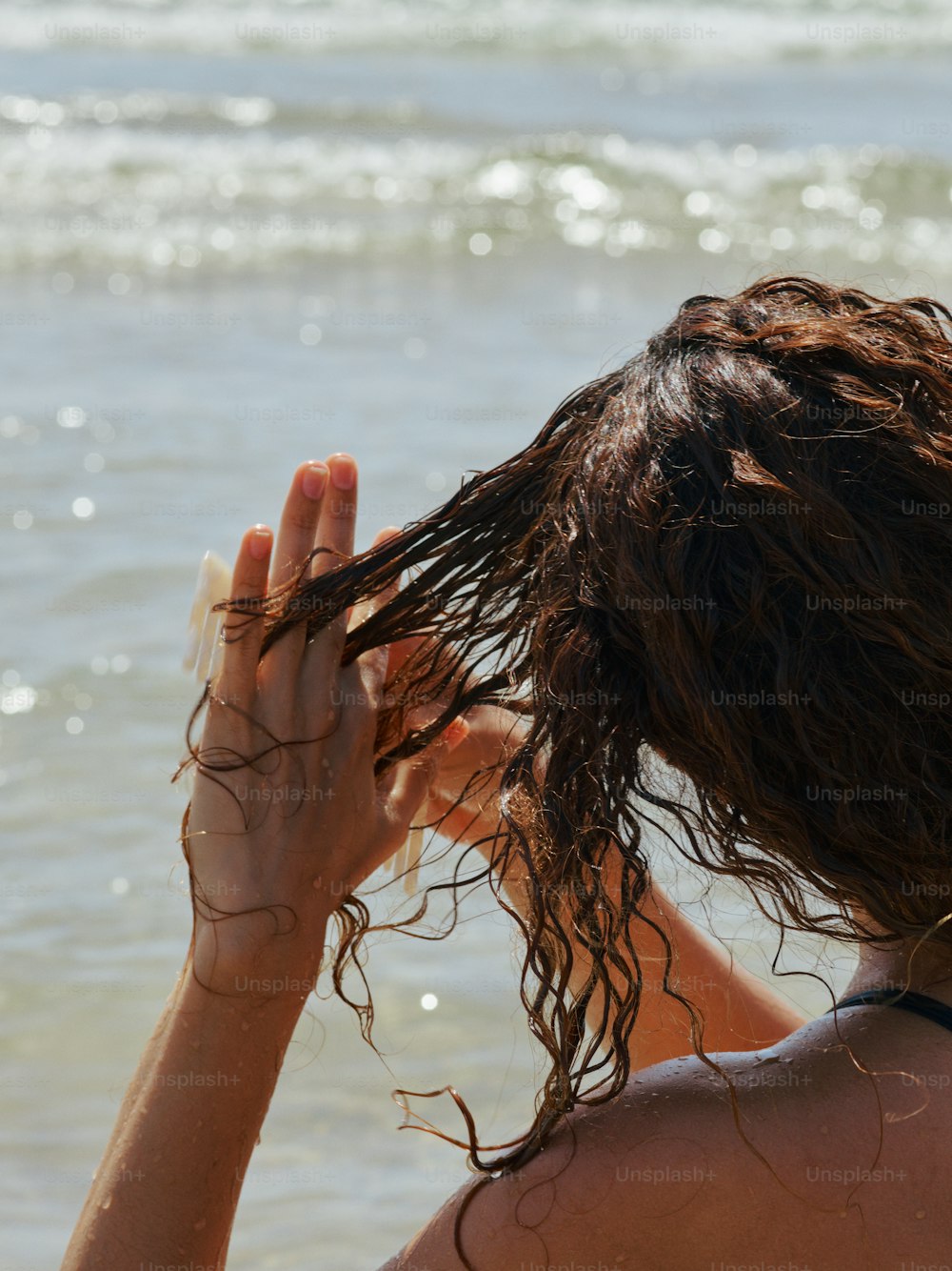 Una donna con i capelli bagnati sulla spiaggia