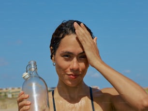 a woman holding a water bottle and covering her eyes