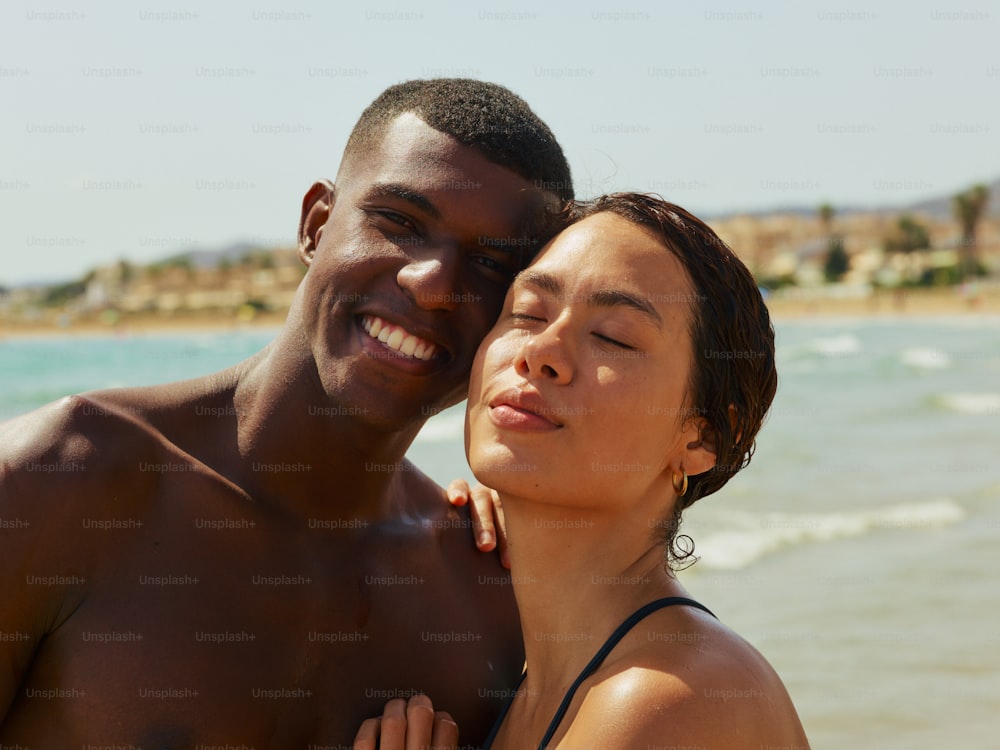 a man and a woman standing next to each other on a beach