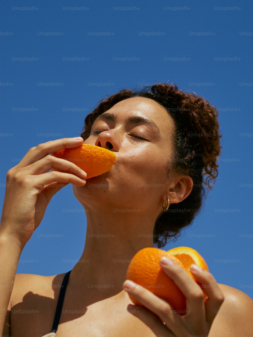 a woman in a bikini eating an orange