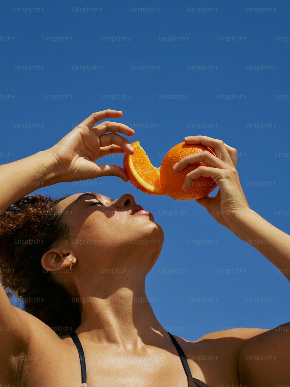 Una mujer en bikini sostiene una naranja