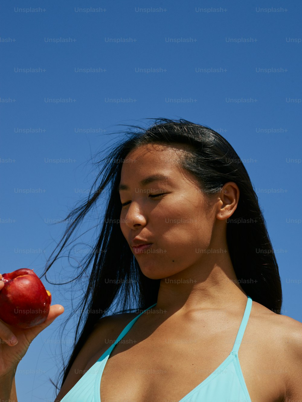 a woman in a bikini holding an apple
