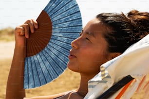 a woman sitting in a beach chair holding an umbrella
