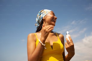 a woman in a yellow bathing suit holding a bottle of sunscreen