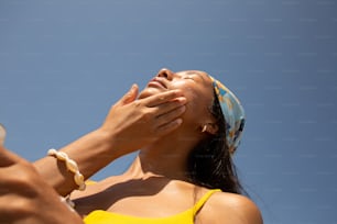 a woman in a yellow top is holding her hand up to her face
