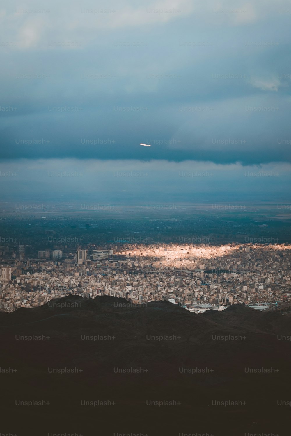 an airplane flying over a city under a cloudy sky