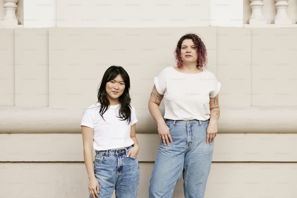 deux femmes debout l’une à côté de l’autre devant un mur