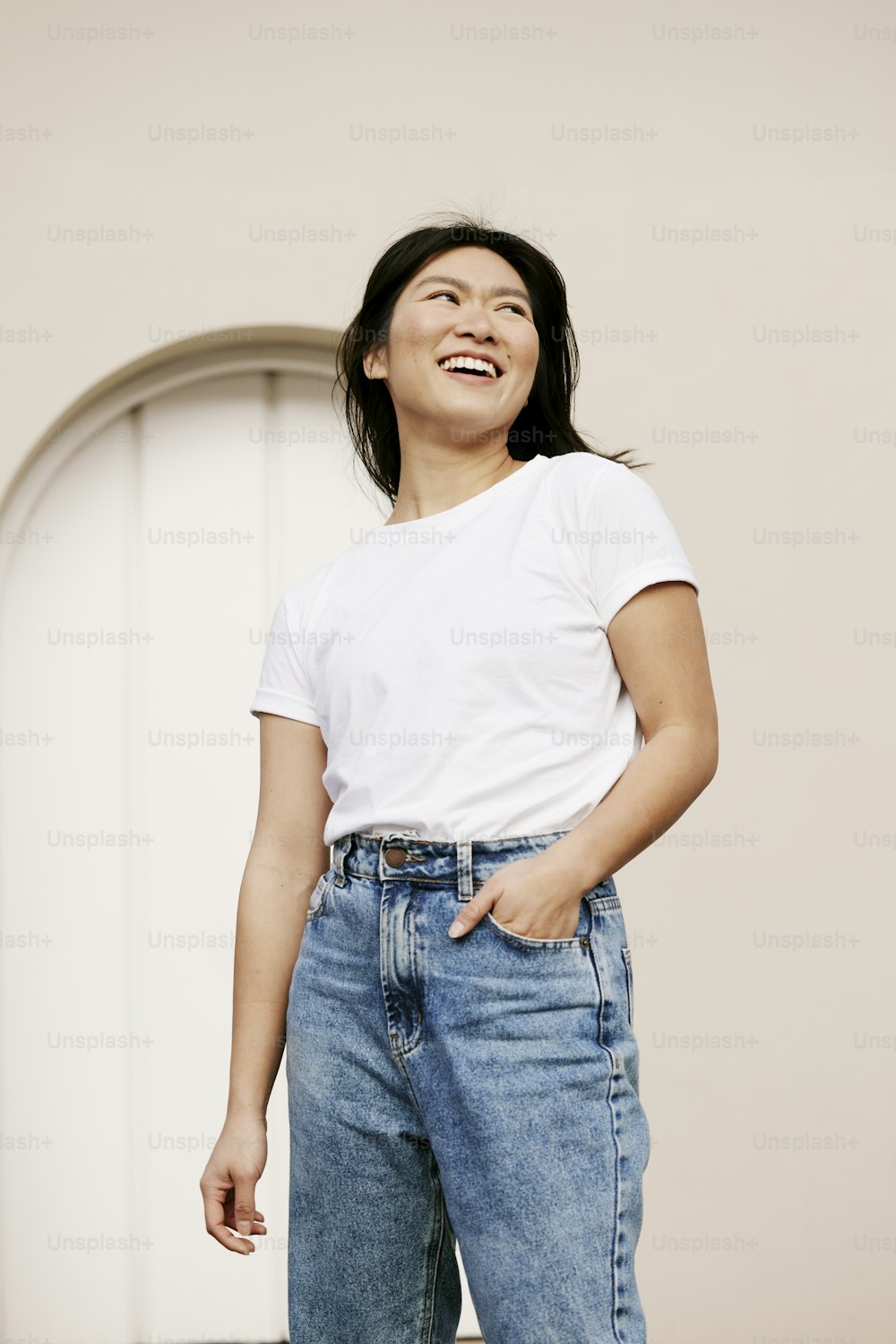 Una mujer con camisa blanca y jeans riendo