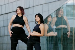 two women standing next to each other in front of a building