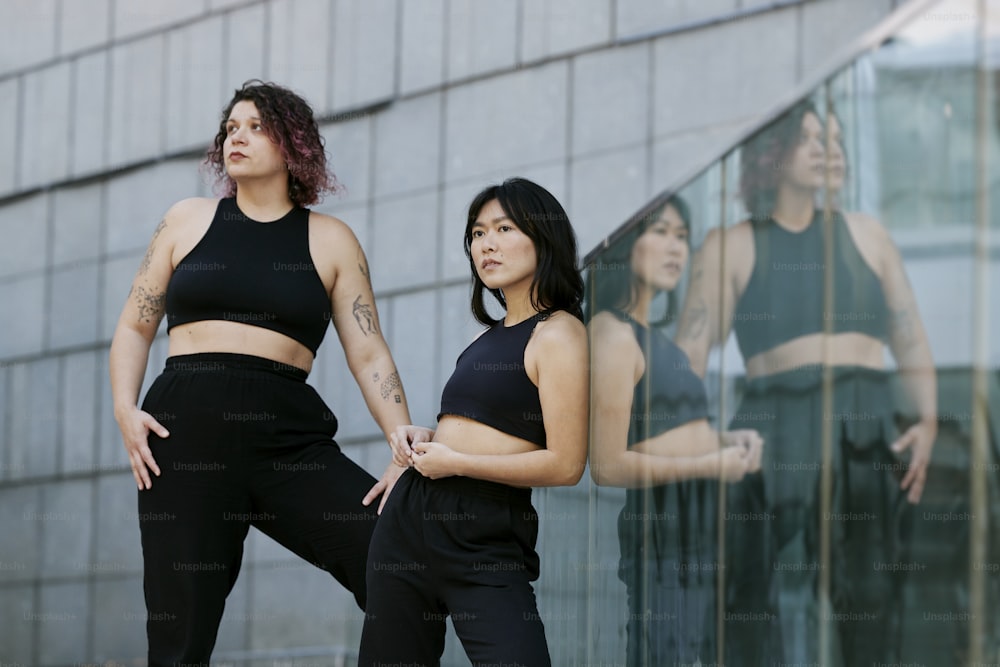 two women standing next to each other in front of a building