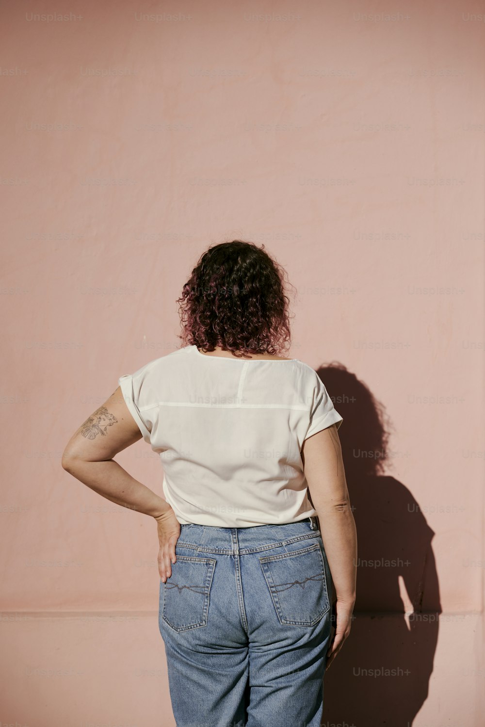 a woman standing in front of a pink wall
