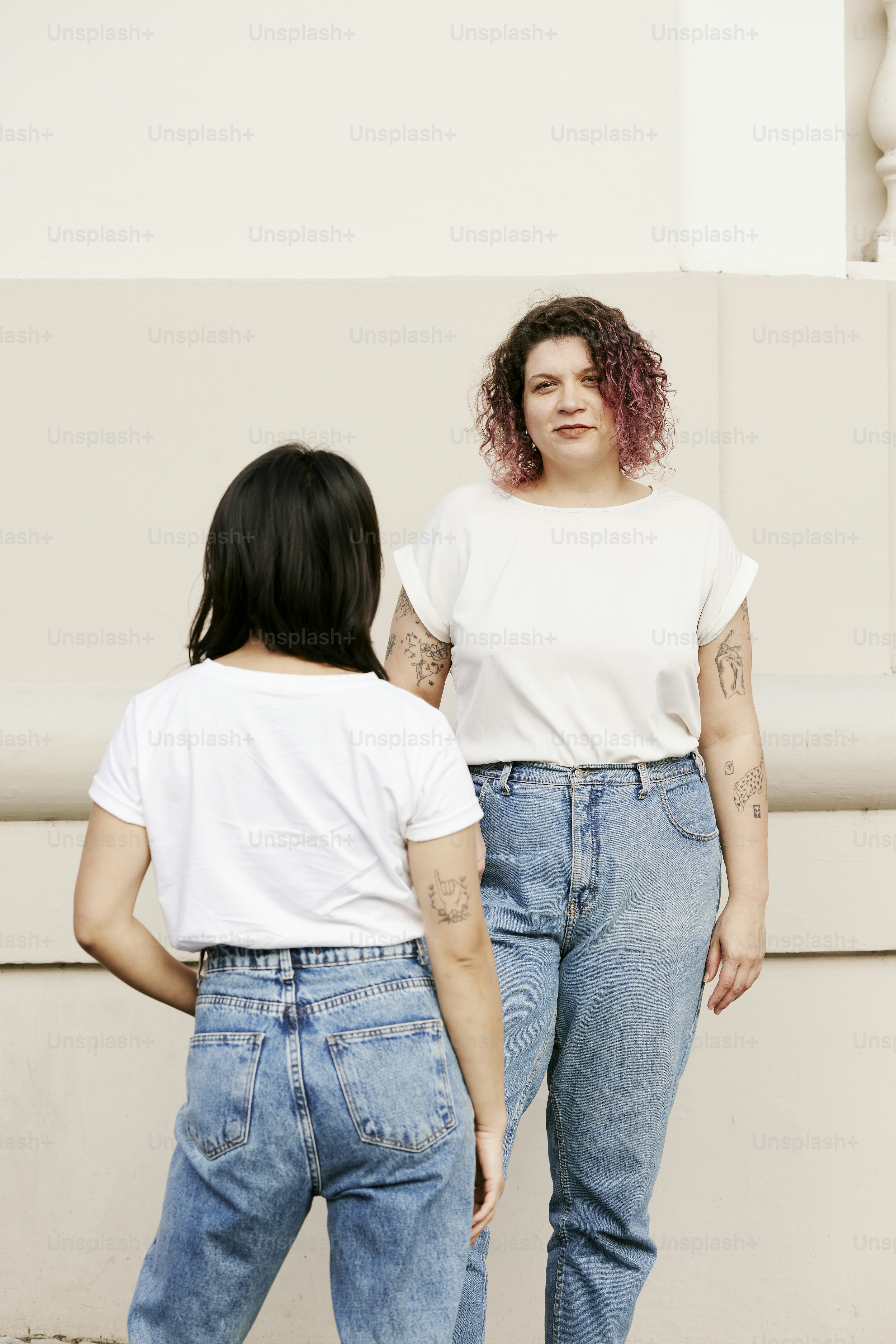 two women standing next to each other in front of a building