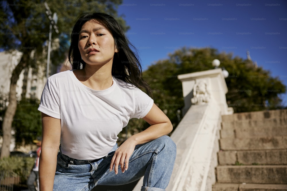 a woman in white shirt and jeans sitting on steps