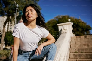 a woman in white shirt and jeans sitting on steps