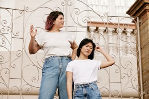 two women standing next to each other in front of a gate