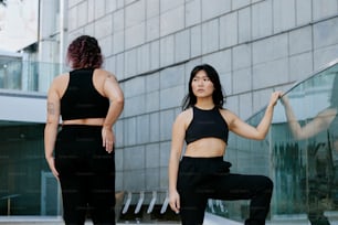 a woman in a black top and black pants standing next to a glass wall