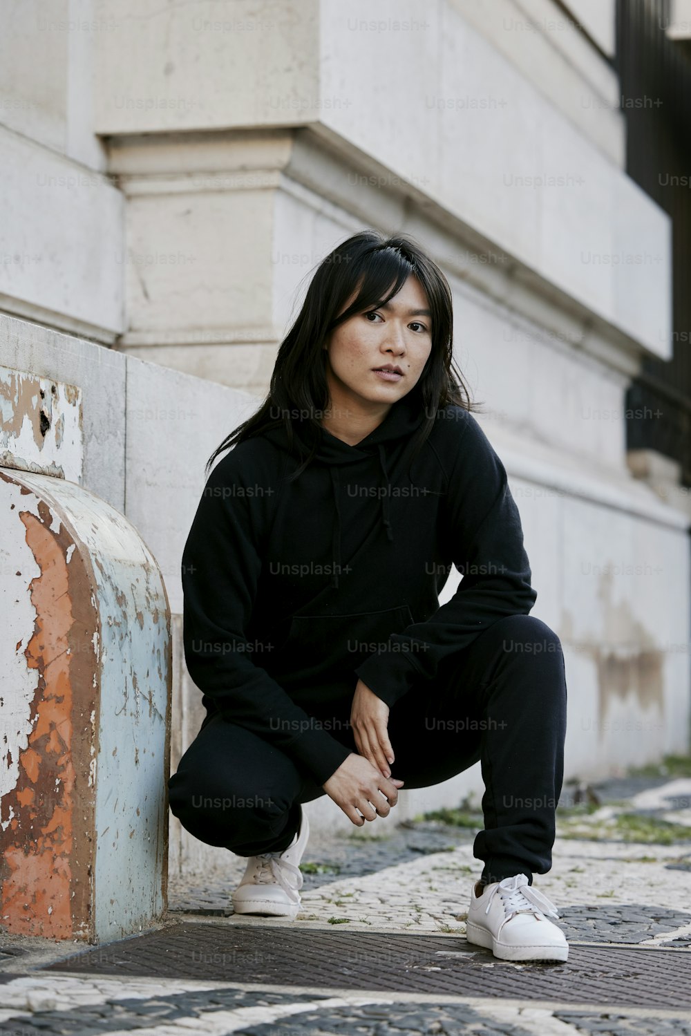 a woman sitting on the ground next to a wall