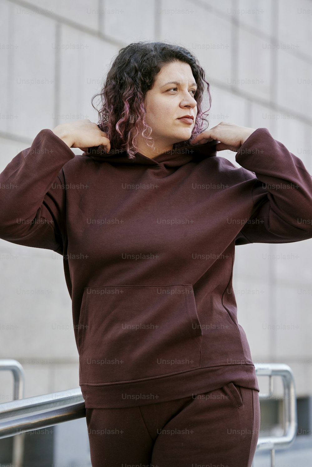 a woman with curly hair wearing a maroon hoodie
