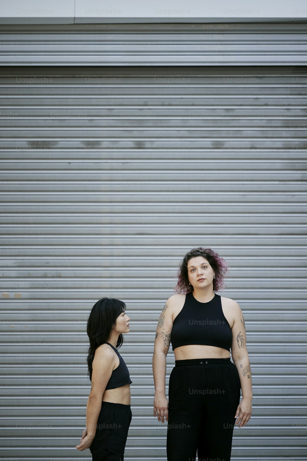 two women standing next to each other in front of a garage door