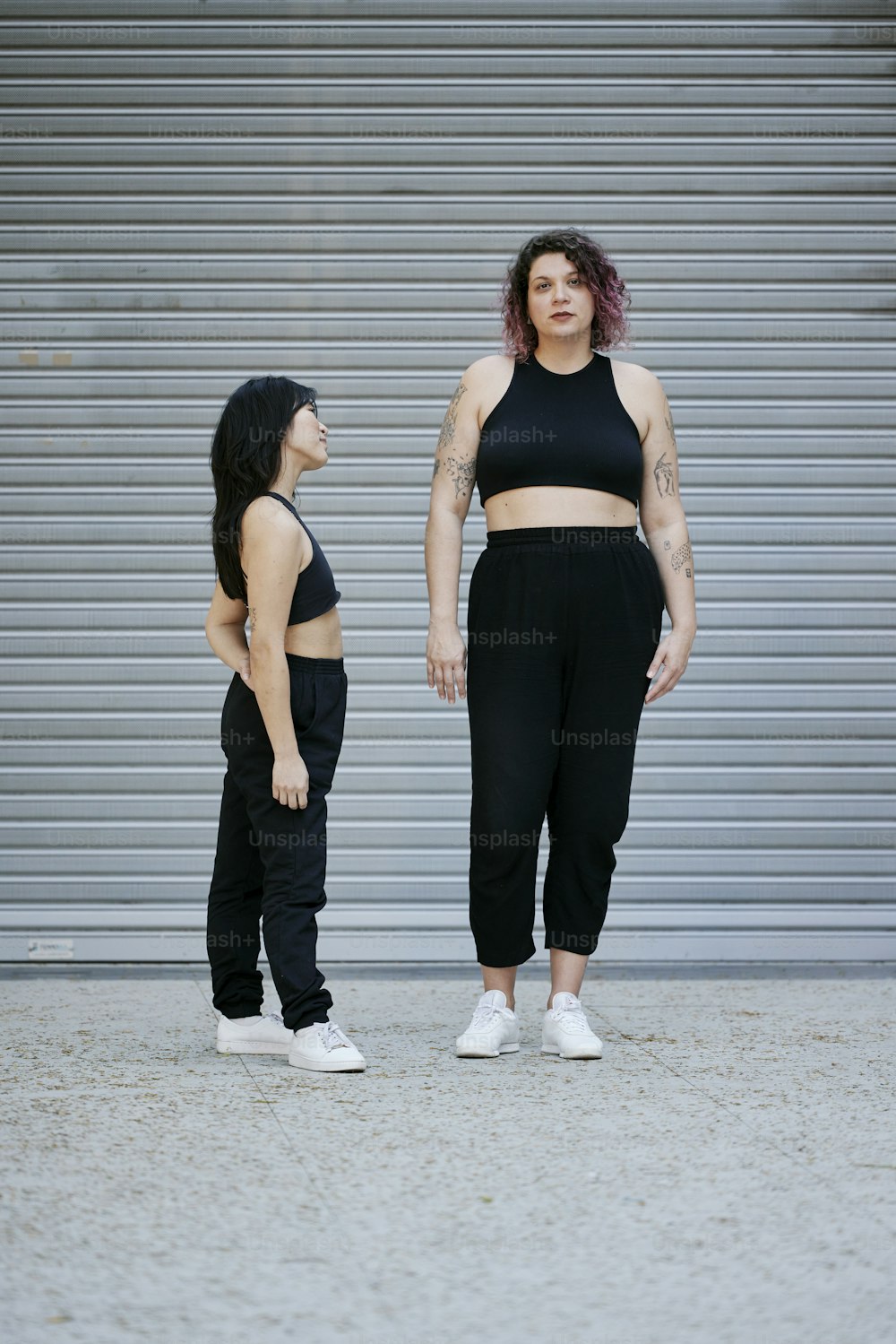 two women standing next to each other in front of a garage door