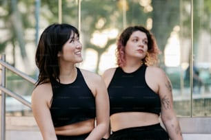 two women standing next to each other in front of a building