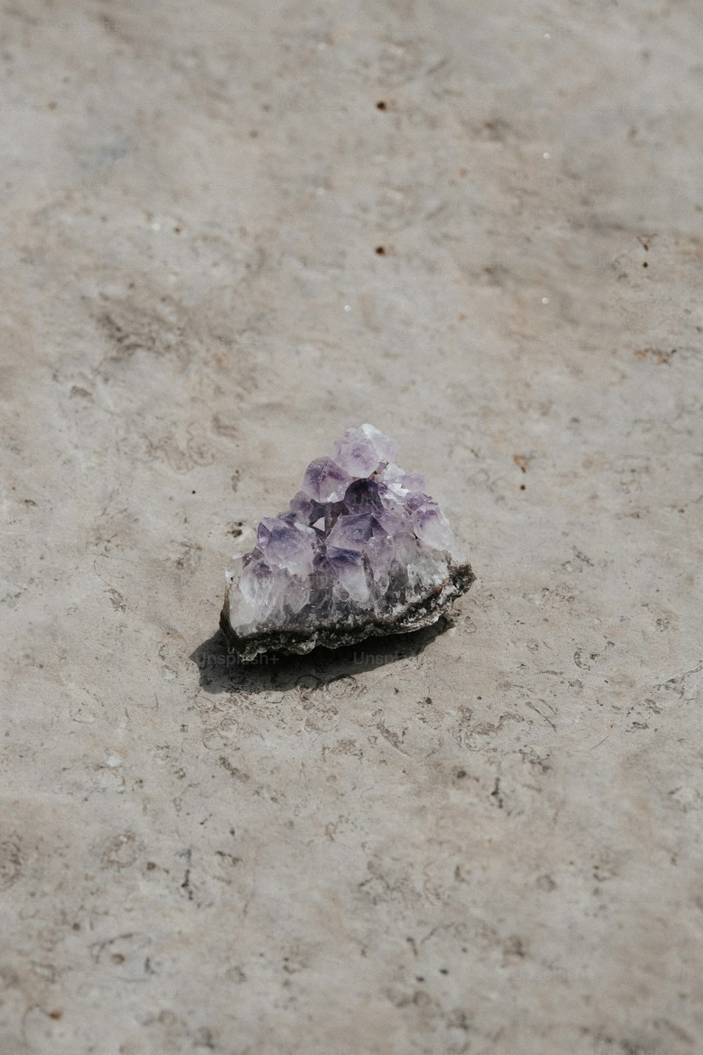 a cluster of purple crystals sitting on top of a cement ground