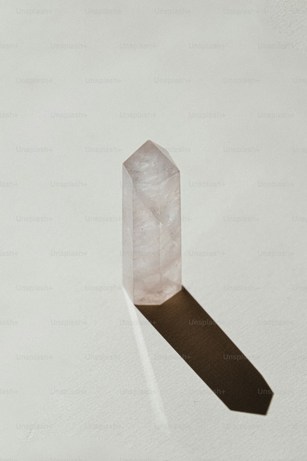 Un solo cristal sobre una superficie blanca con una sombra larga