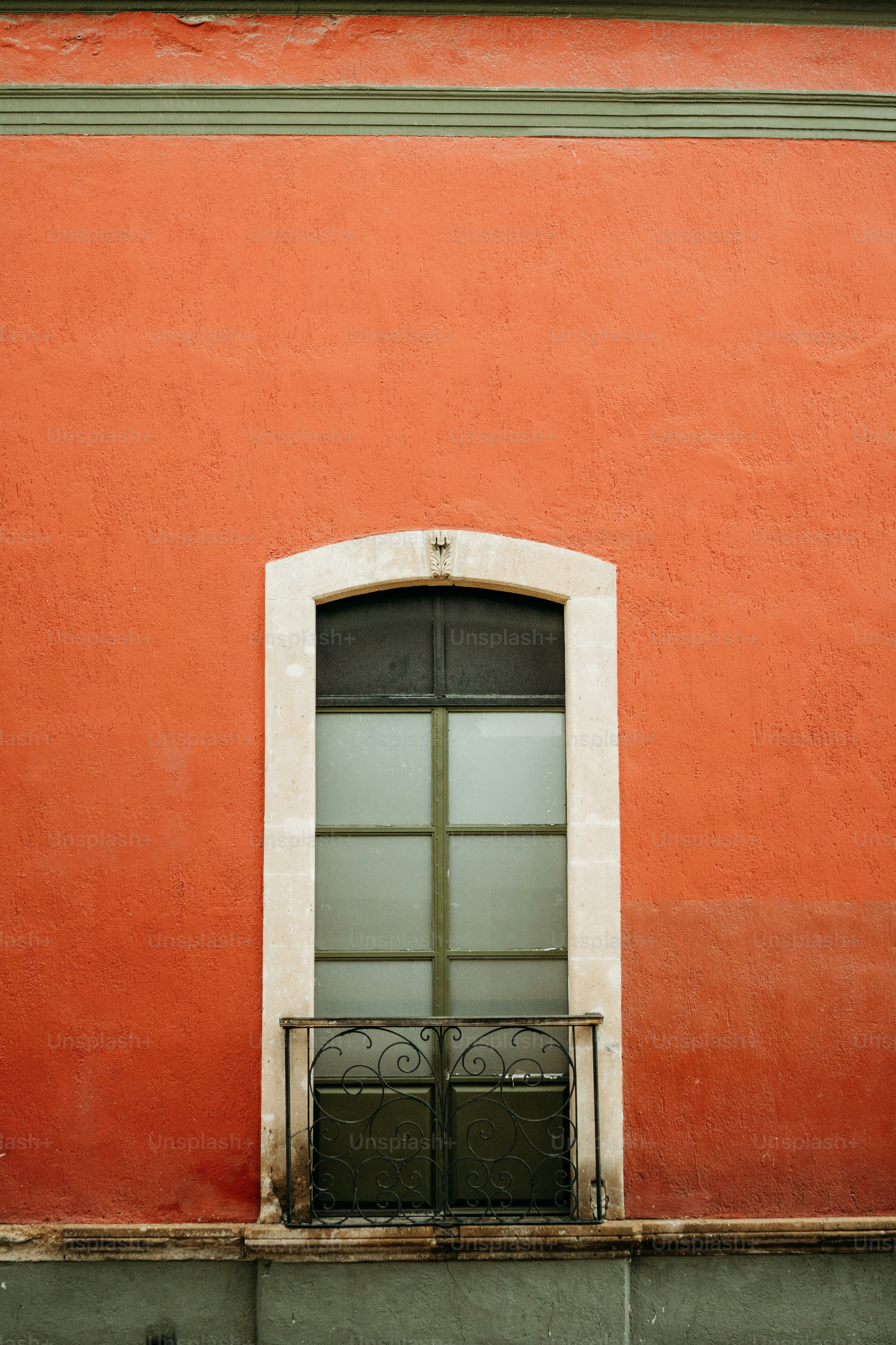 Un edificio rojo con una ventana blanca y una puerta verde