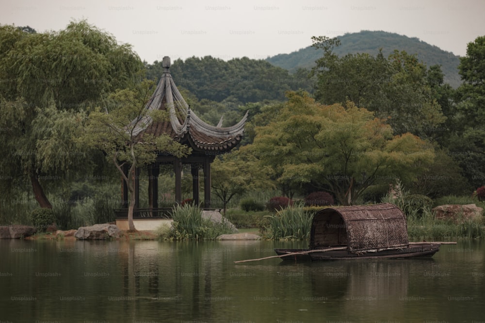 a boat floating on top of a lake next to a pavilion