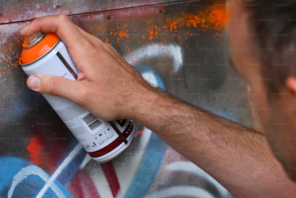 um homem spray pintando grafite em uma parede