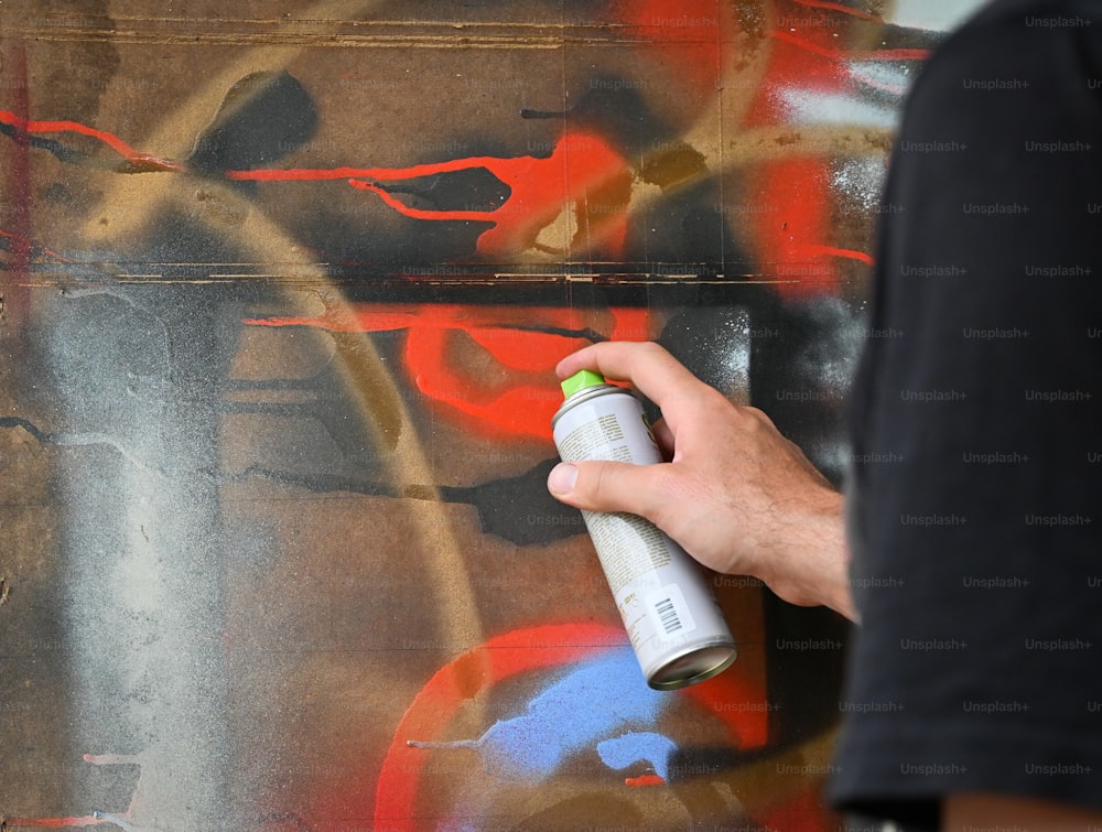 a person spray painting a wall with graffiti