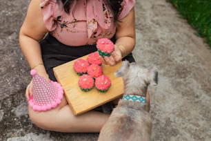 a woman holding a tray of cupcakes next to a dog