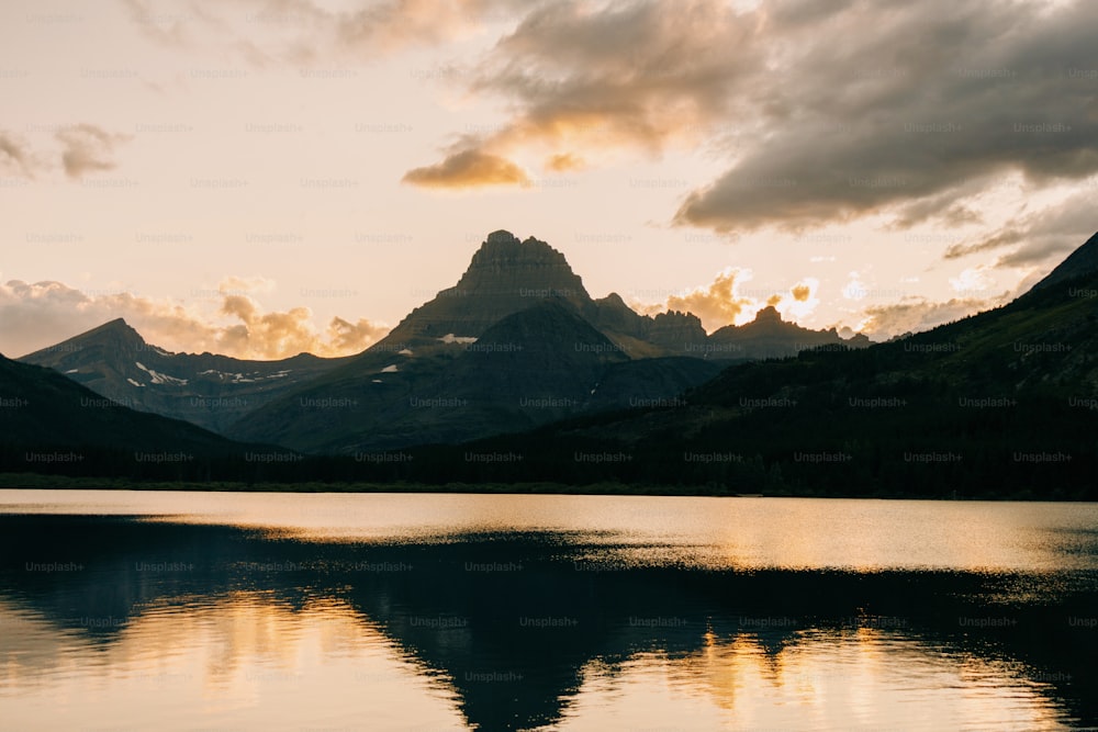 the sun is setting over a mountain lake